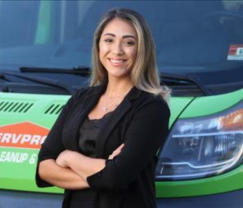 woman with brown hair standing in front of a green truck