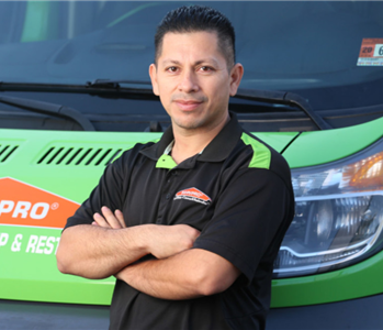 man with short black hair standing in front of a green truck
