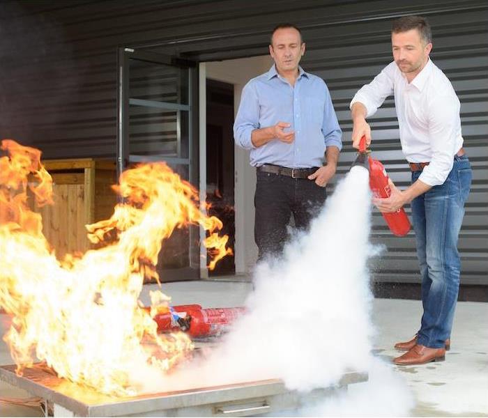 two men using a fire extinguisher to put out a fire